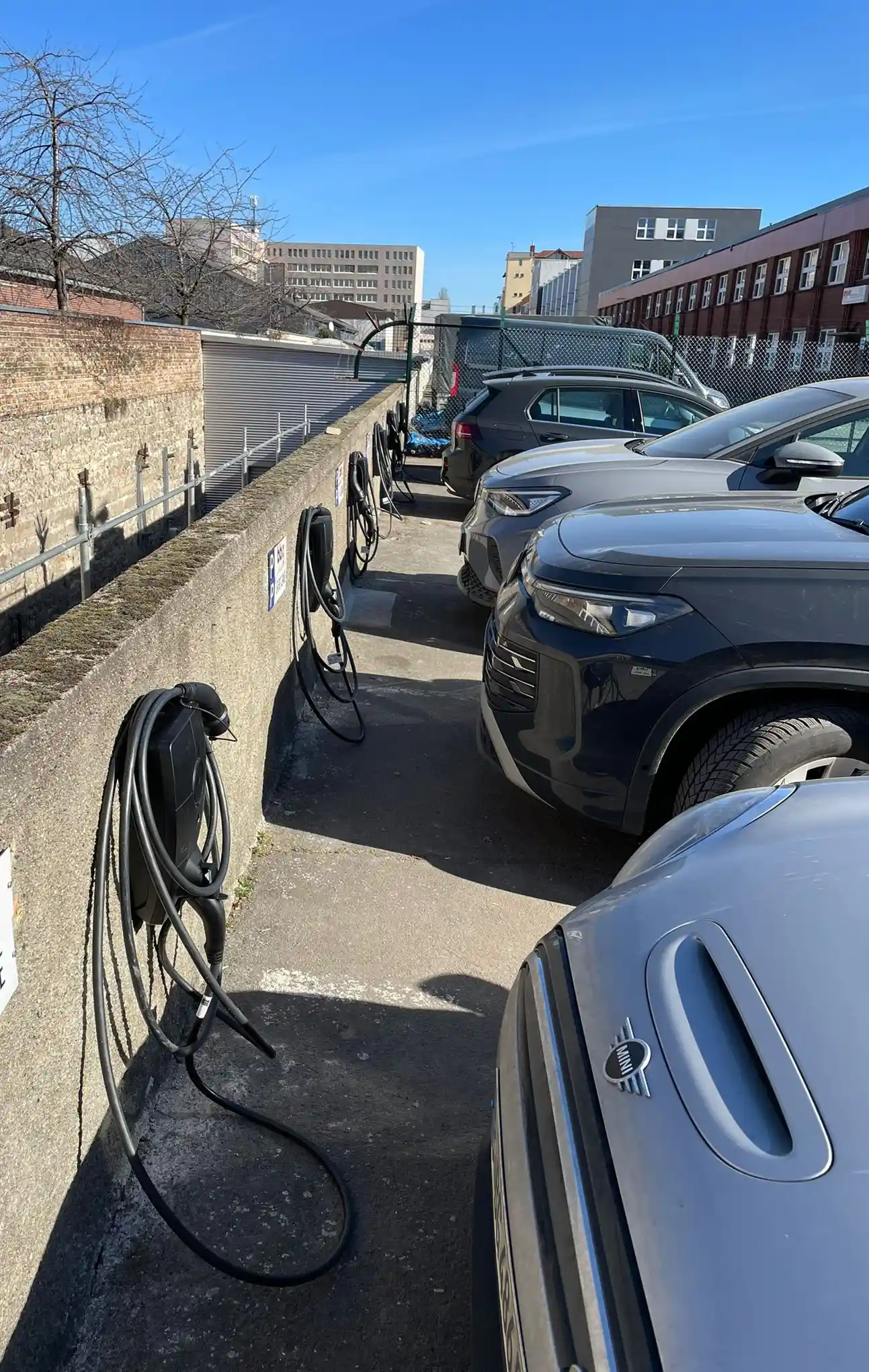 Wallboxen an einer Mauer mit ladenden Elektroautos auf dem Gelände einer Berliner Baugenossenschaft